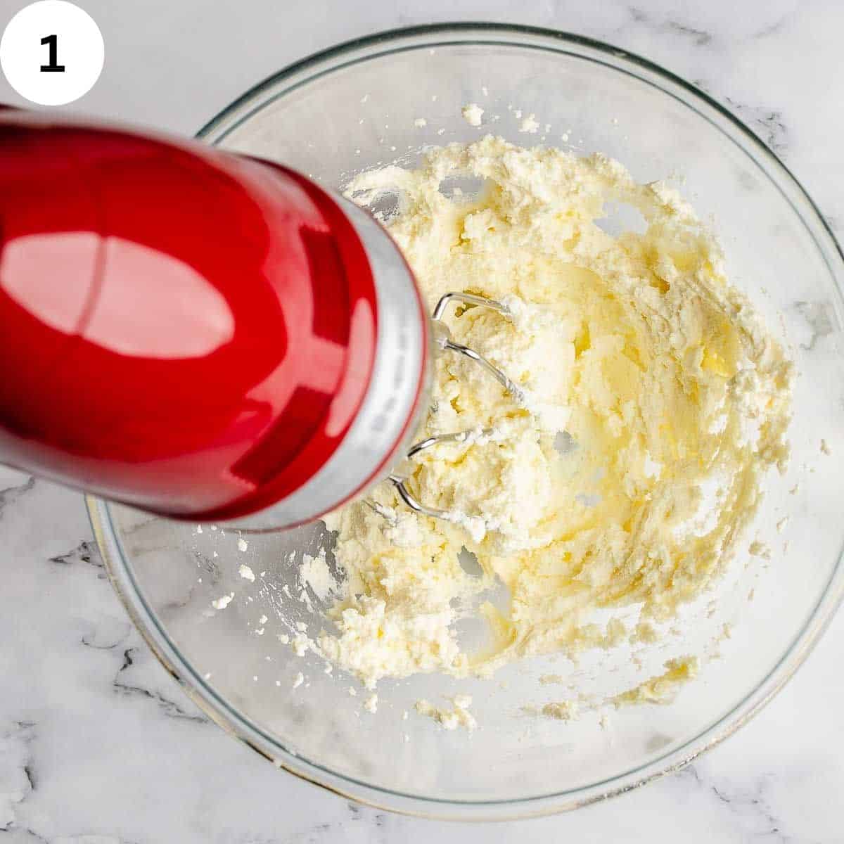 Beating ricotta cheese with an electric hand held mixer.