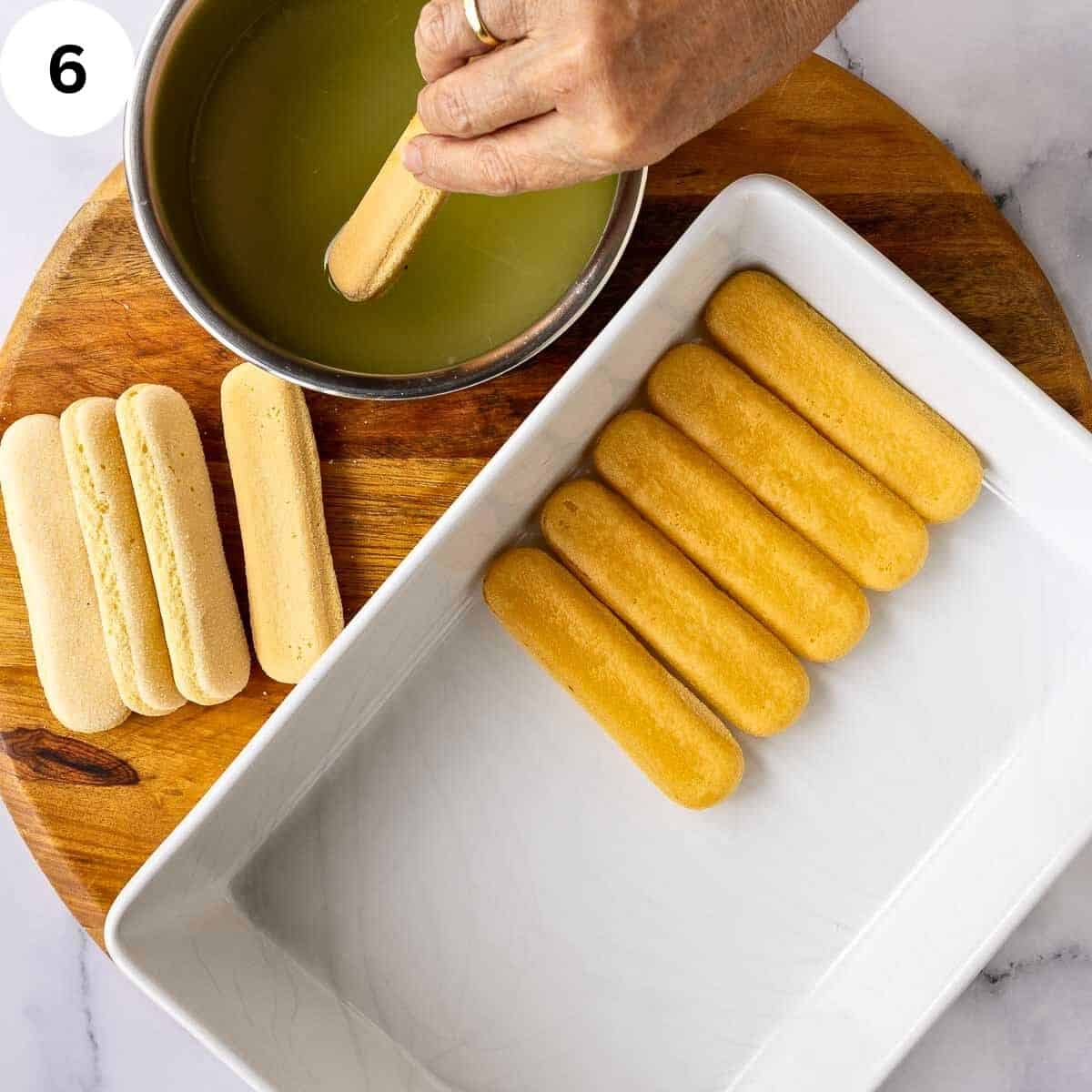 Dipping savoiardi cookies into a limoncello sugar syrup and lining a dish with them.