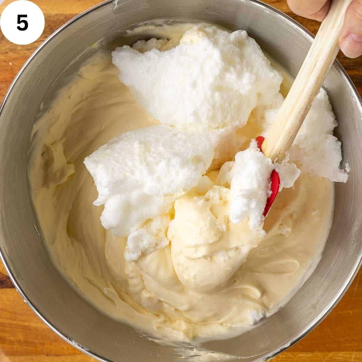 Folding whipped egg whites into a creamy egg yolk mixture.