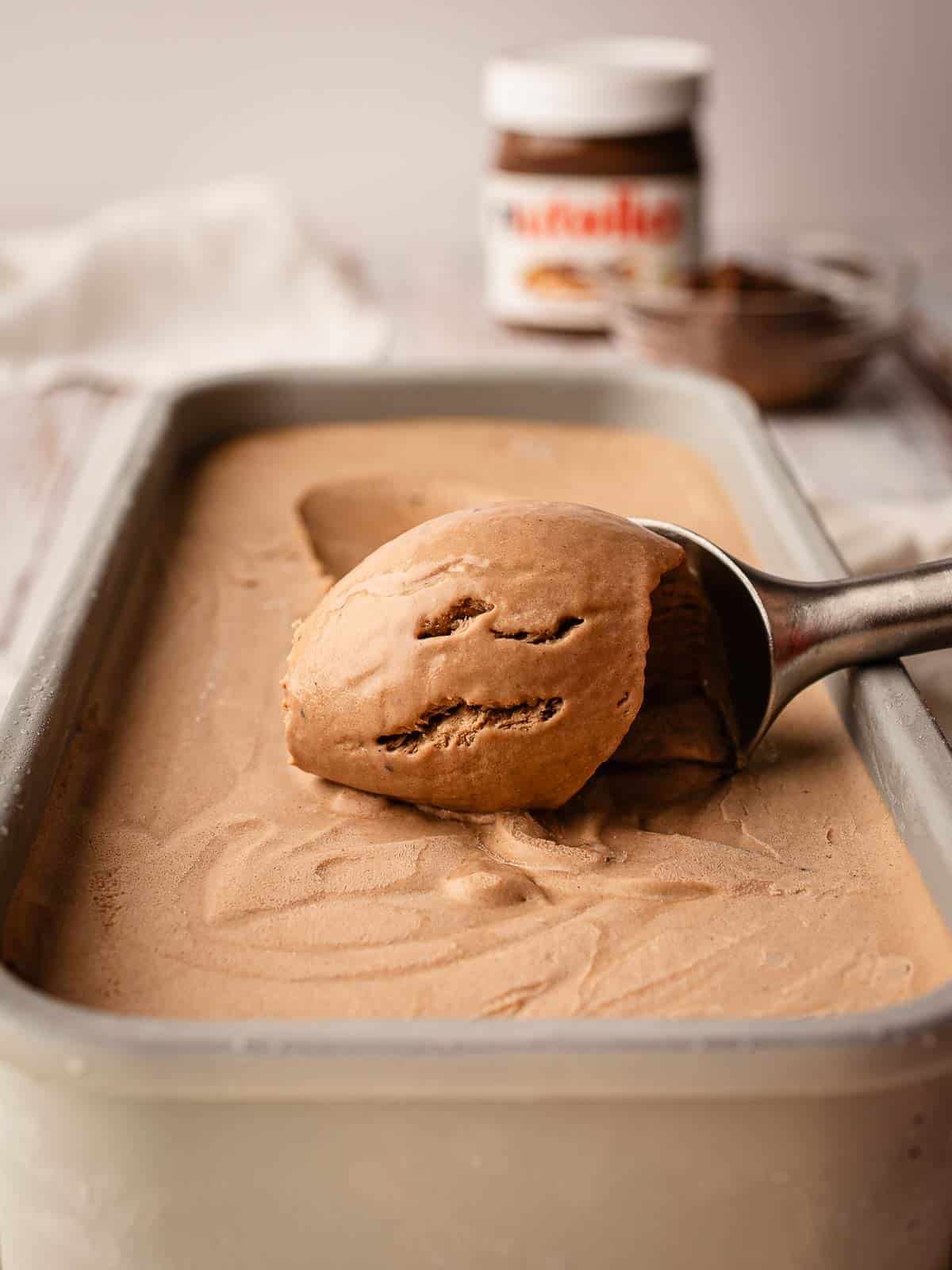 Scoop being pulled through chocolate ice cream in a loaf pan