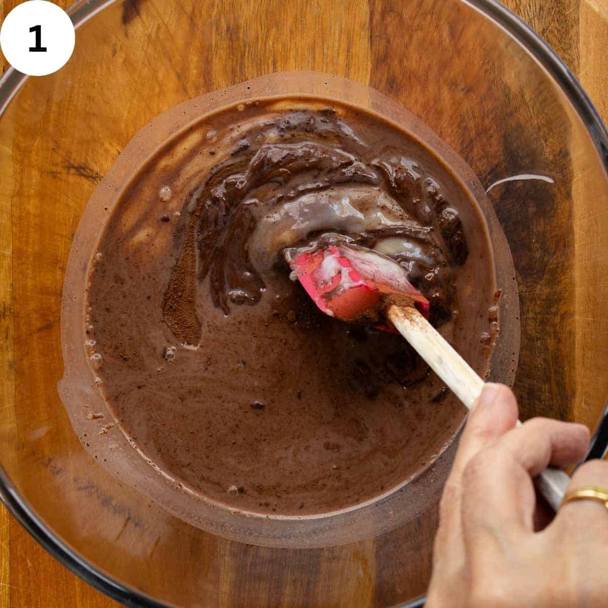 Stirring a chocolate mixture in a glass bowl.