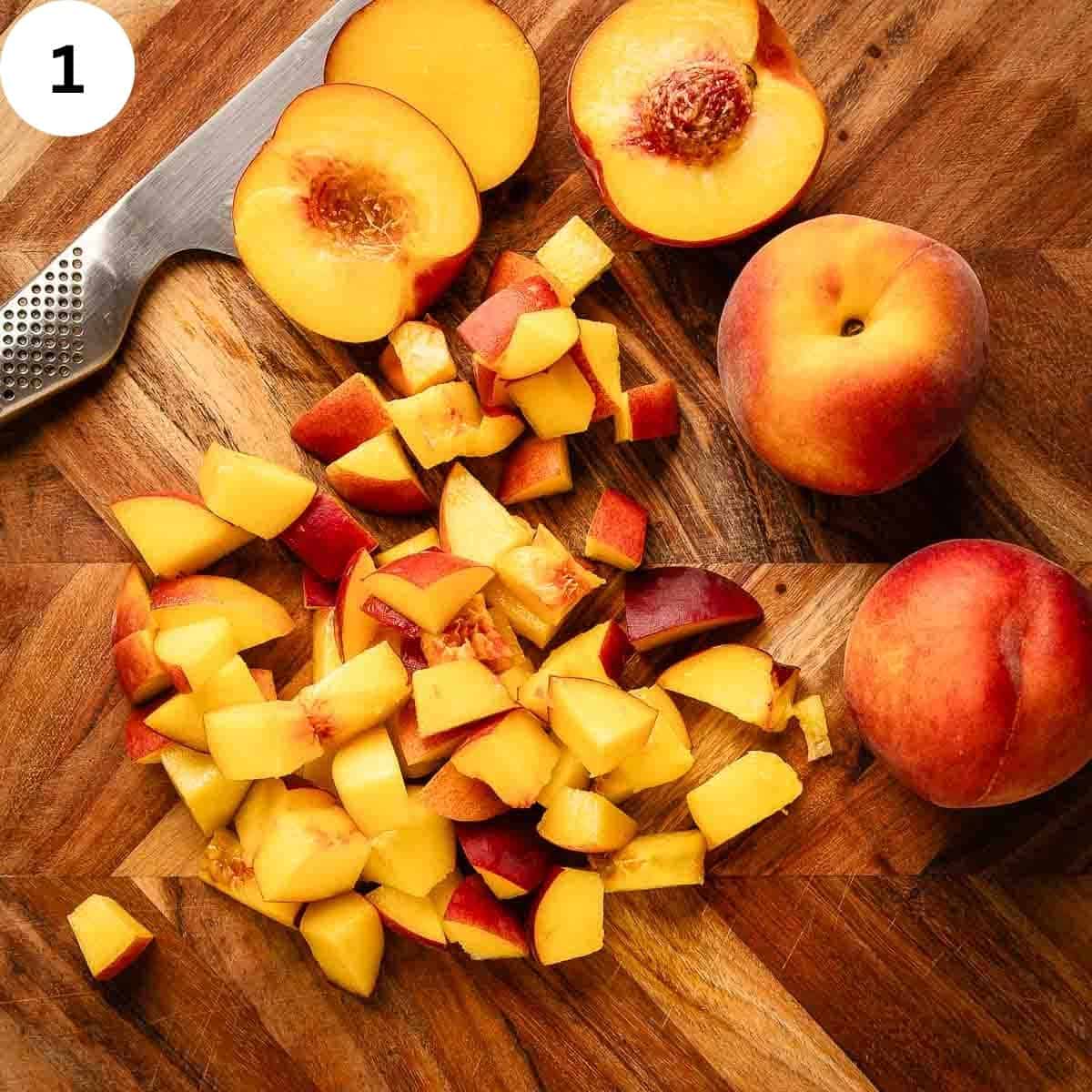Whole peaches, halved peaches and chopped peaches on a wooden board.