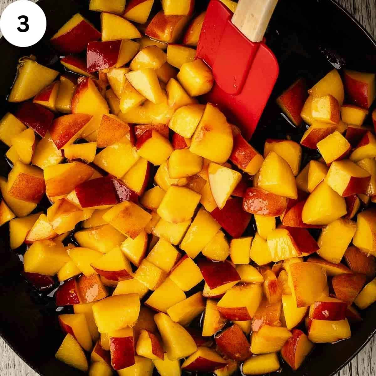 Stirring chopped peaches in a skillet.